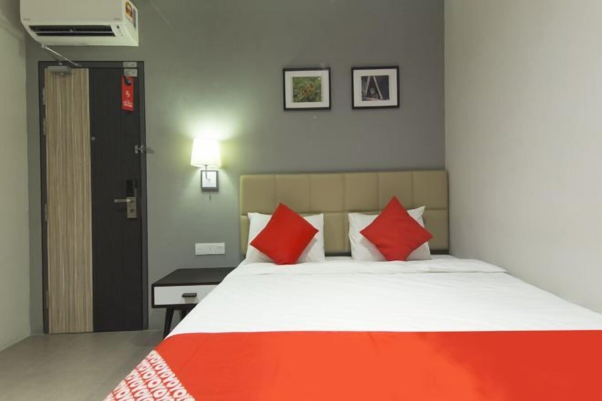 Ein Hotelzimmer mit einem Bett, einem Nachttisch, einer Wandlampe und einer Tür.