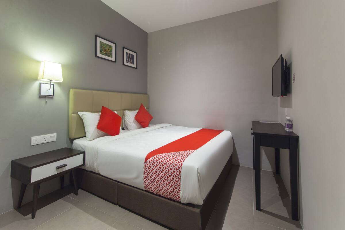 Ein Hotelzimmer mit Bett, Nachttisch, Fernseher und einer Wandlampe.