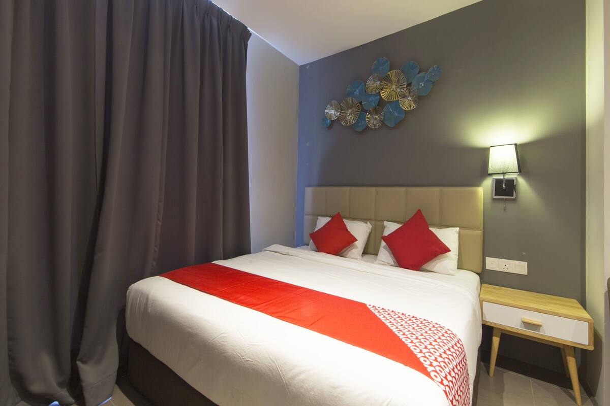 Ein Hotelzimmer mit Bett, Nachttisch, Lampe und Wandbild.