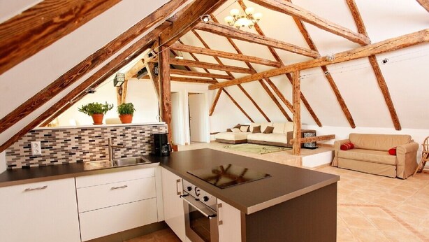 Een keuken met een centraal kookeiland, witte kasten en een betegelde achterwand.