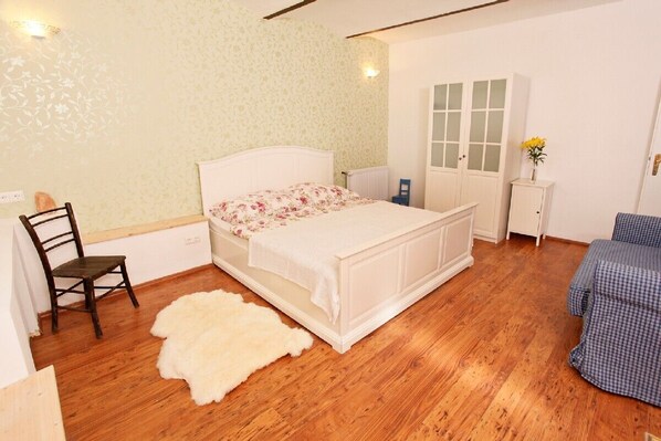 A bedroom with a bed, a chair, a radiator, a wardrobe, and a small table with a vase. - High modern bondet with antique, 200 meter to the lake, 10 Minutes to skicourse (Villach)