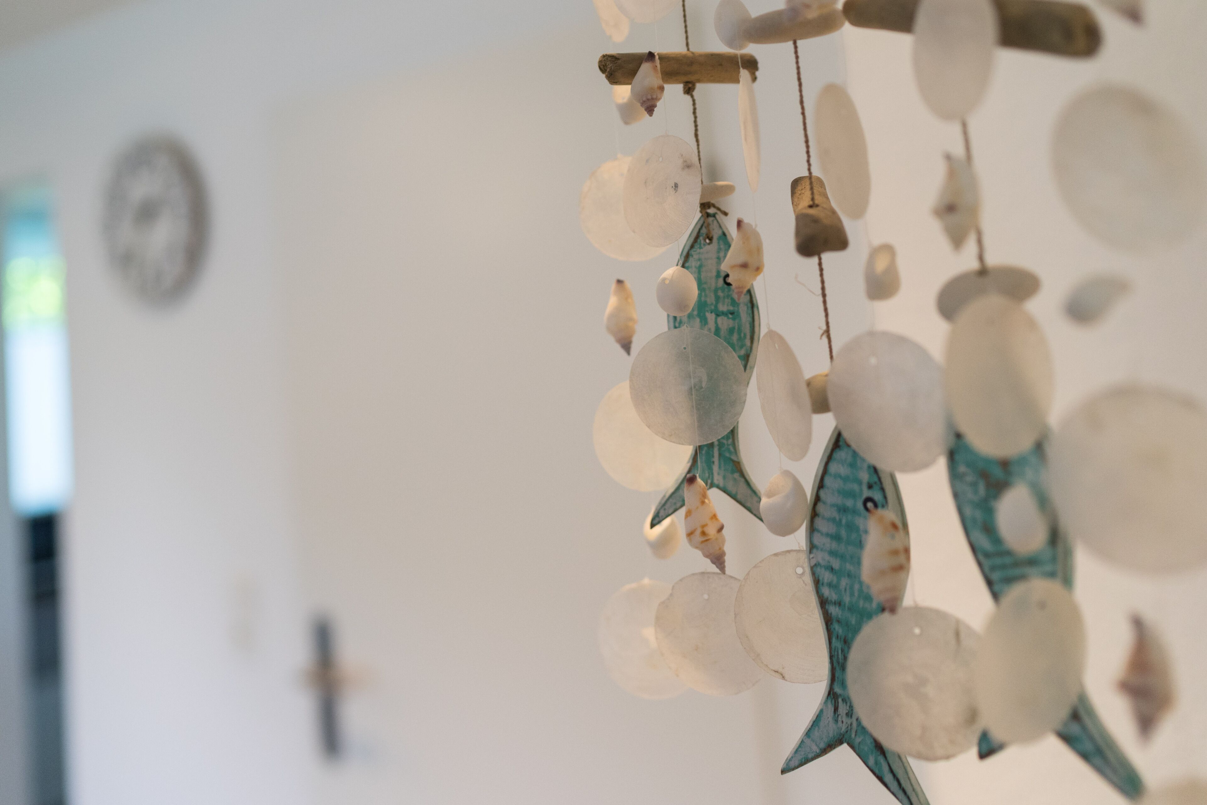 Une décoration murale composée de coquillages et d’une croix en bois.