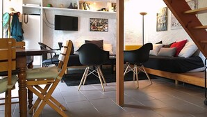 A cozy living room with a wooden table, two black chairs, a sofa, and a staircase leading to an upper level. - MONNA - Maison à Logonna Daoulas - BR4001 (Logonna-Daoulas)