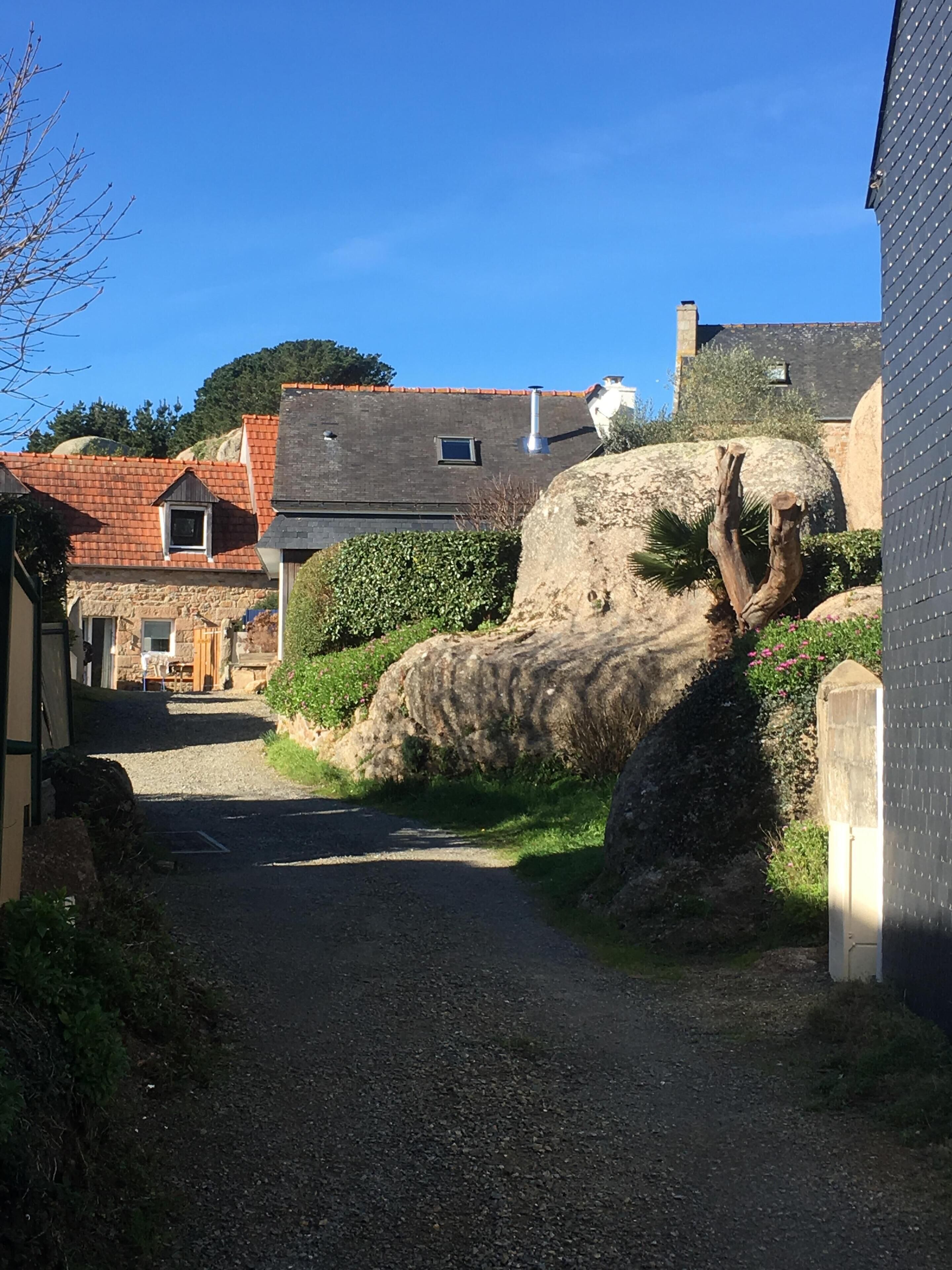 A narrow gravel path leading to a stone building with a sloped roof.
