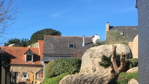 Ein schmaler Kiesweg führt zu einem Steinhaus mit geneigtem Dach.