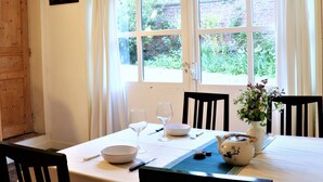 A dining table set with a bowl, wine glasses, a knife, a teapot, and a vase with flowers. - Charming house with flower garden (beach 10min walk) (Dieppe)