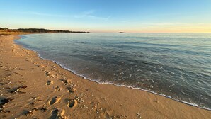 Una spiaggia con impronte sulla sabbia e un mare calmo.