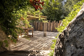Ein hölzerner Pergola mit Kletterpflanzen, einem Tisch und einem rustikalen Gartenzaun.
