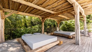 Eine Holzterrasse mit zwei Betten, einem Geländer und Blick auf einen Wald.