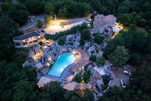 An aerial view of a property with a swimming pool, a stone building, and a modern house.