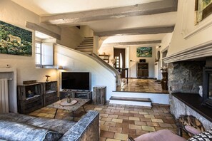A spacious living area with a fireplace, a television, and a staircase leading to another level.