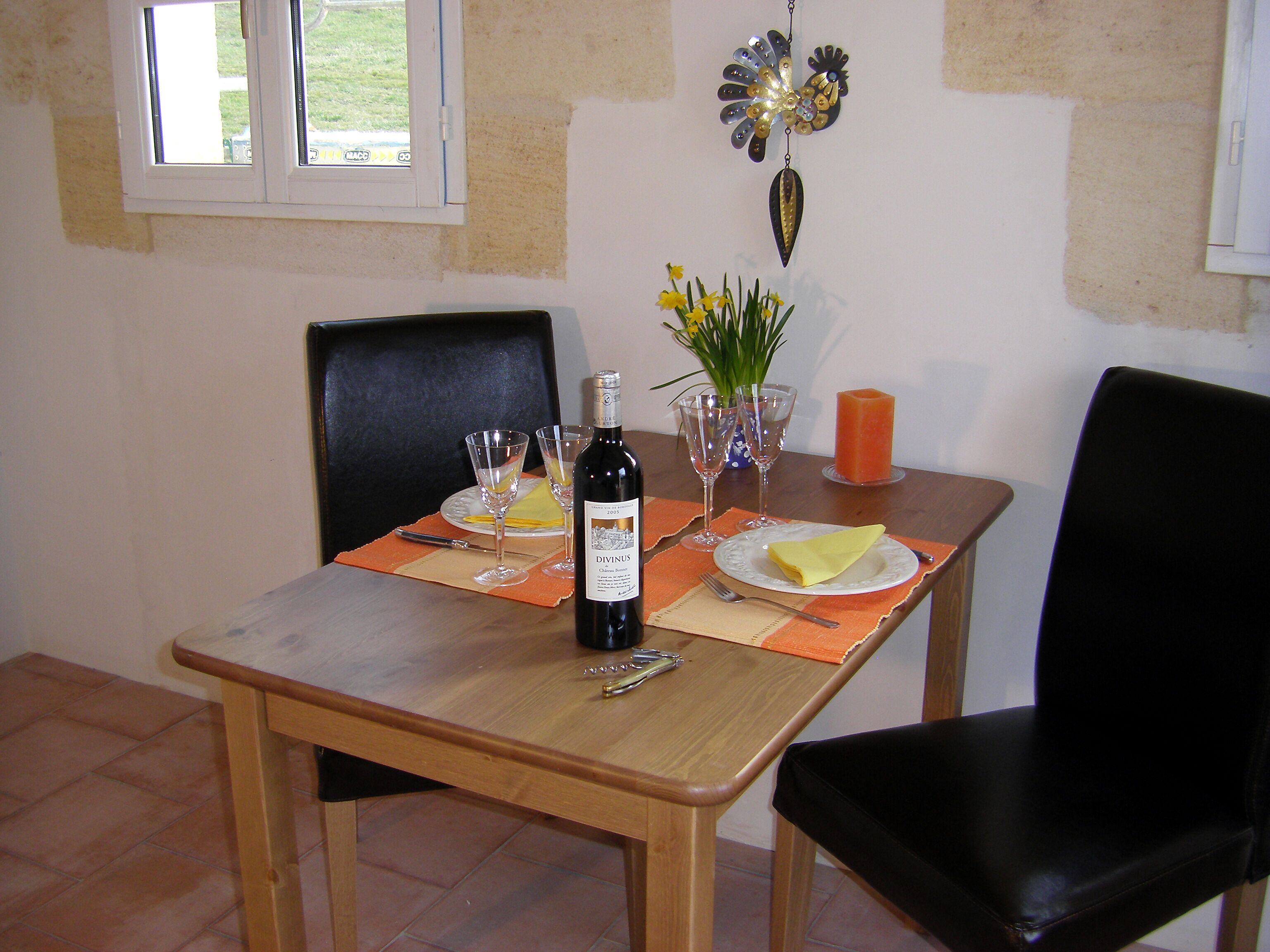 Una mesa de comedor puesta con platos, vasos, una botella y cubiertos.