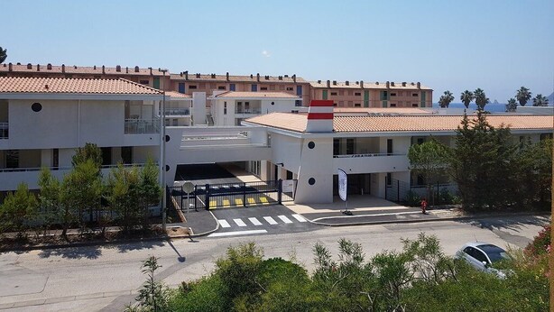 Un hôtel à plusieurs étages doté d’une cour intérieure, de balcons et d’un espace de stationnement.