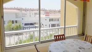 Un balcon donnant sur des immeubles et une table recouverte d’une nappe.