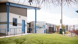 Un edificio con facciata blu e bianca, una piscina e un'area recintata con palme.