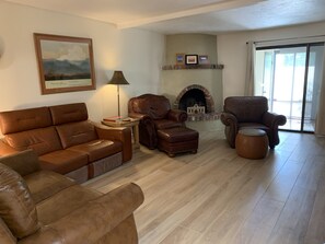 A living room with a fireplace, leather sofas, and a large window.