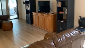 Un soggiorno con un divano in pelle, una televisione su un mobile in legno e scaffali.