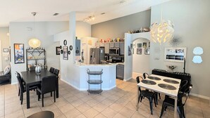 A modern kitchen with a central island, dining area with a round table, and a living space with a sofa and coffee table. - Stay in a Star Wars-themed vacation home in Emerald Island Resort near Disney. This family-friendly Kissimmee getaway features a private pool and spa, game room, smart-lock check-in, and room for your group to relax after the parks. (Kissimmee)
