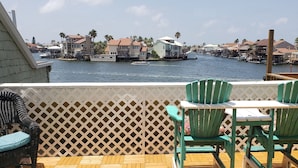 A balcony with a view of a marina, featuring wooden decking and green chairs. - REEL Paradise! <br>*Perfect Couple's Retreat or Big Fun For A Small Family* (Corpus Christi)