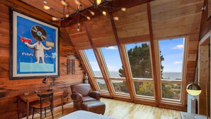 A bedroom with a large bed, a wooden desk, a leather chair, and a large window offering a view of the outdoors. - Country Home in Bolinas (Bolinas)