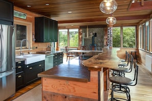 A modern kitchen with a central island, wooden cabinets, and a large window providing a view of the outdoors. - Country Home in Bolinas (Bolinas)