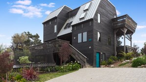 A modern multi-story building with a unique architectural design, featuring a prominent staircase and a balcony. - Country Home in Bolinas (Bolinas)