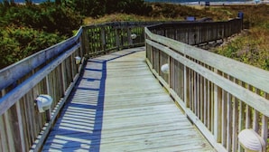 A wooden boardwalk leading to a beach with a clear view of the ocean.