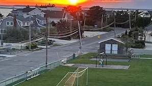A residential area with houses, a soccer field, and a sunset.