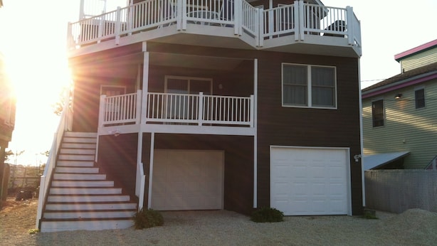 A two-story house with a front garage, a balcony on the upper floor, and a staircase leading to the entrance.