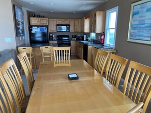 A modern kitchen with wooden cabinets, a stainless steel refrigerator, a microwave, and a stove. There is a dining table with chairs and a window providing natural light. - Beautiful Ocean & Bay Views - 3 Decks, 2 MBR Suites, 2 LRs, park/playground (Beach Haven)