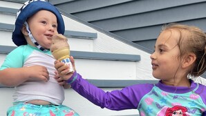 Two children sitting on steps, one holding an ice cream cone.