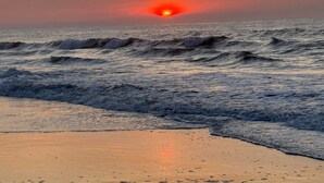 A beach with waves and a sunset.
