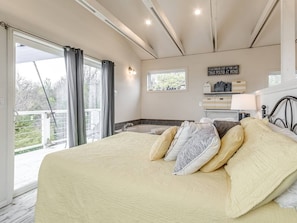 A bedroom with a large bed, a window, a bathtub, and a sign on the wall. - Romantic Lakeview Treehouse with Jacuzzi Tub, Loft & Private Balcony (Stigler)
