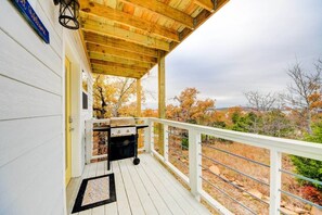 A covered porch with a grill, a white railing, and a view of trees in the background. - Romantic Lakeview Treehouse with Jacuzzi Tub, Loft & Private Balcony (Stigler)
