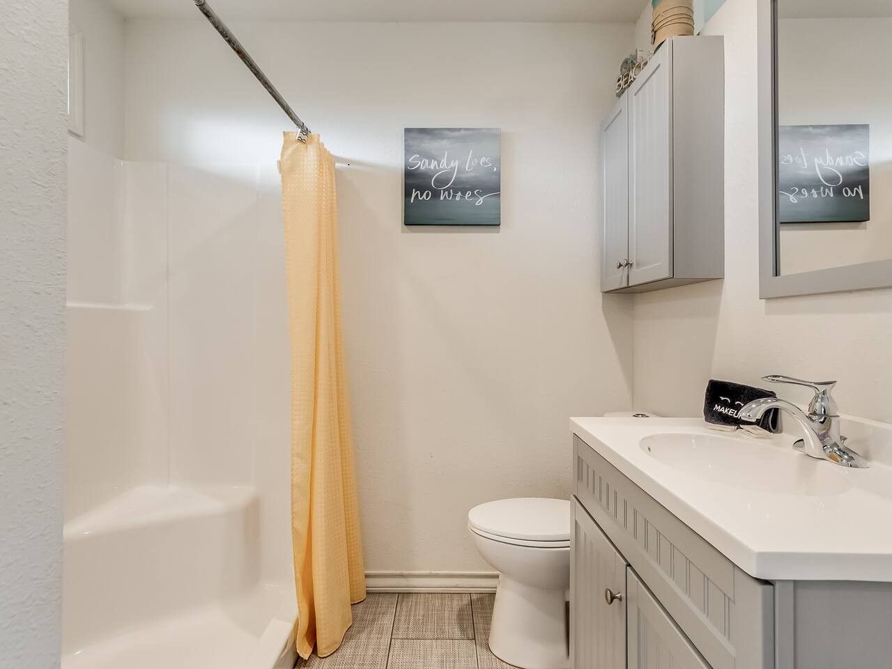 A bathroom with a bathtub, toilet, and sink. There are two wall-mounted signs with text.
