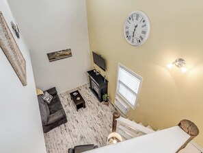 A living room with a sofa, a coffee table, a TV, and a clock on the wall.