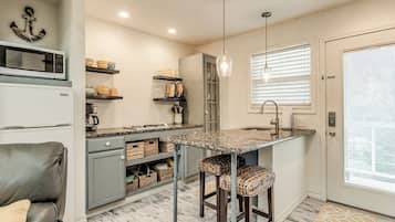 A compact kitchen with a central island, built-in appliances, and a seating area with a couch and stools.