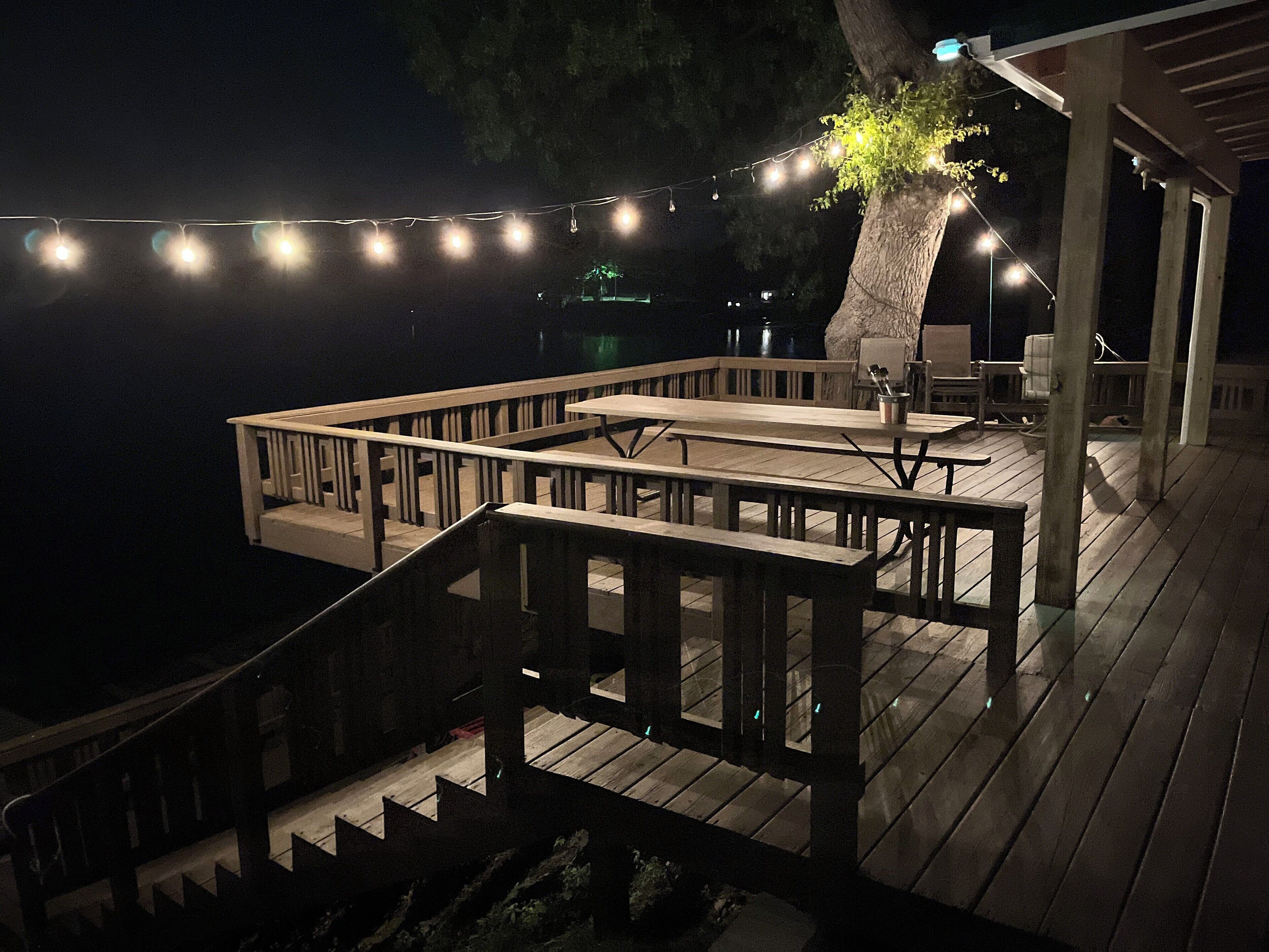 A wooden deck with outdoor seating and string lights.
