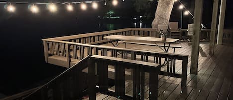 A wooden deck with outdoor seating and string lights.