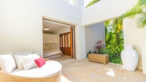 Quarto moderno com cama, um sofá de vime com almofadas, uma planta em vaso e um vaso grande.