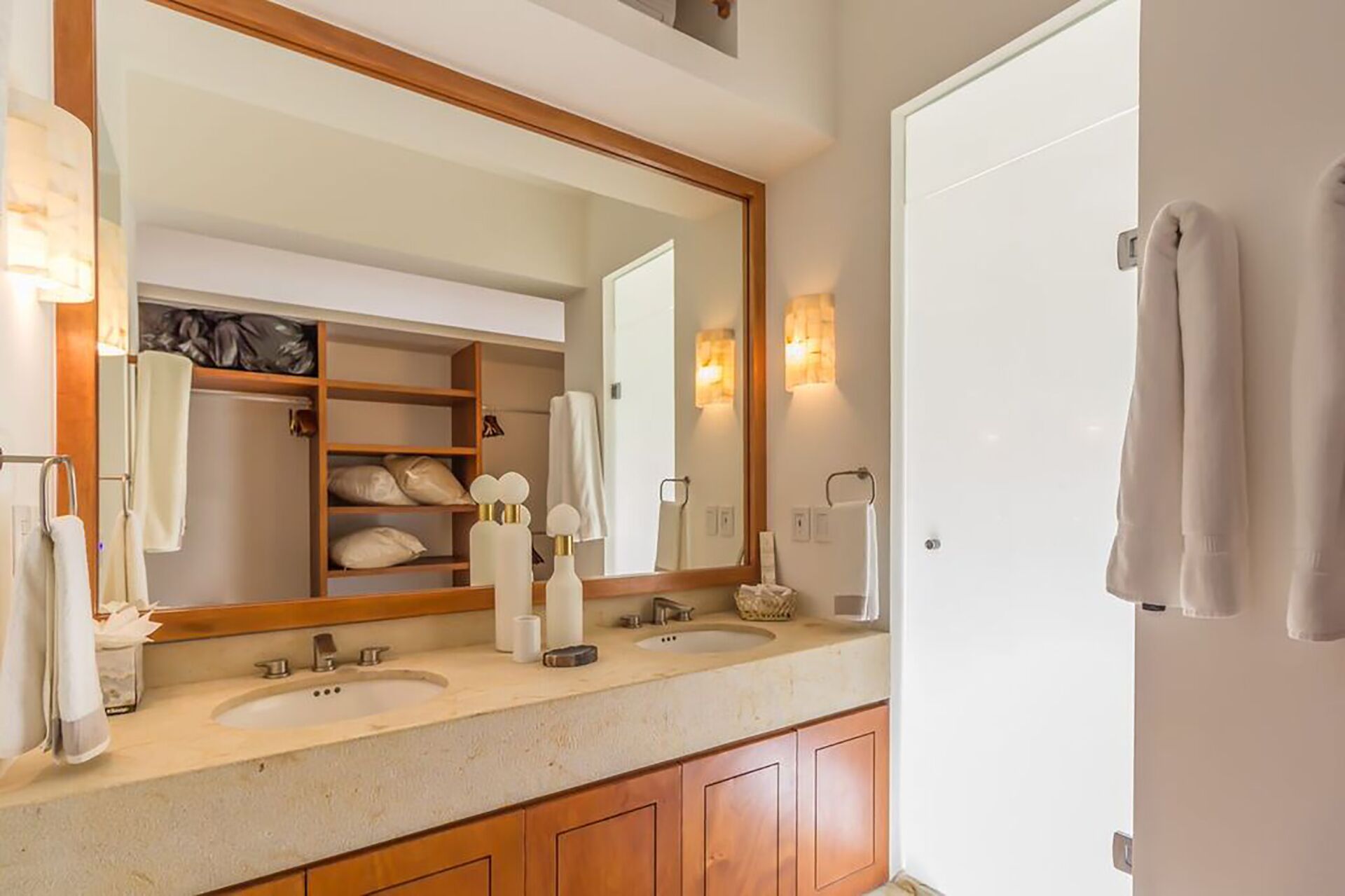 A bathroom with two sinks, a large mirror, and a wooden cabinet below the countertop.