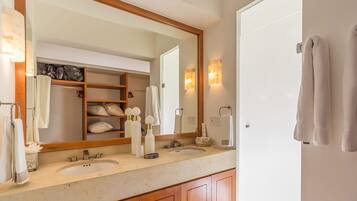 A bathroom with two sinks, a large mirror, and a wooden cabinet below the countertop.