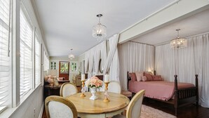 Une chambre avec un grand lit, une table à manger en bois avec des chaises et un lustre.