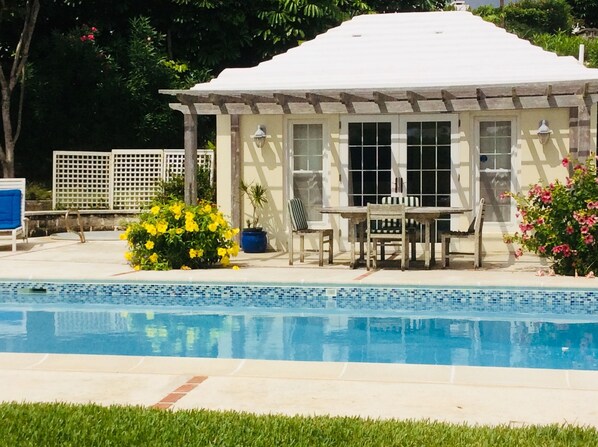 A poolside area with a covered seating area, a pool, and surrounding greenery. - Pool House Studio In A Garden Setting + EV chargers (Smiths)