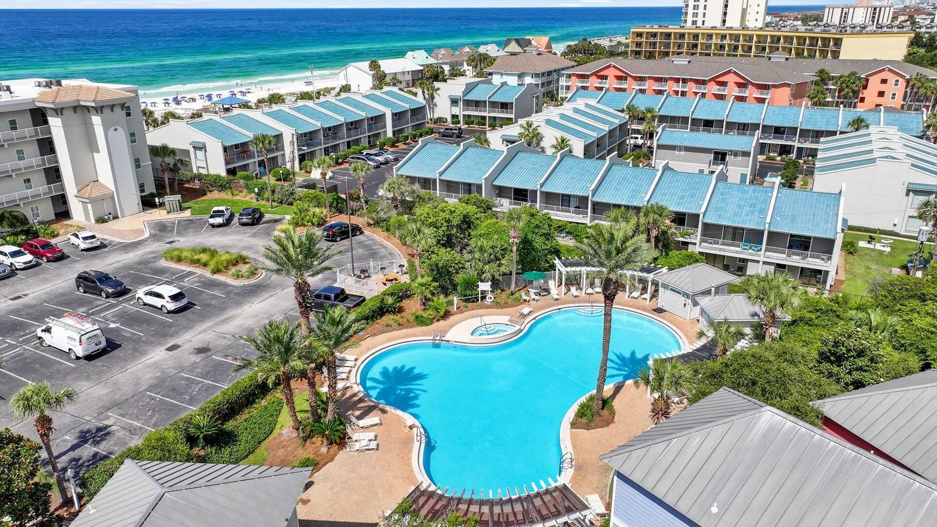 A resort with a swimming pool, beach access, and multiple buildings with blue roofs.