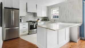 A modern kitchen with white cabinetry, stainless steel appliances, and a large island. - Private Courtyard + Steps from King St +Parking Included (Charleston)