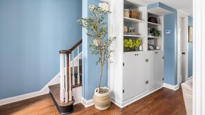 A hallway with blue walls, a wooden staircase, a white storage unit, and a potted plant. - Private Courtyard + Steps from King St +Parking Included (Charleston)