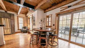 Interior de madera con barra central, ventanas amplias y vistas a la zona de mesas al aire libre.