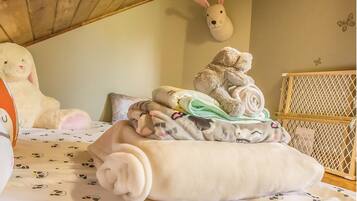 Cozy bedroom with a plush toy, patterned blanket, and crib, perfect for families or individuals seeking a warm and inviting stay.
