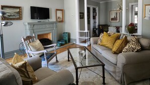 A living room with a fireplace, a television, and a sofa with patterned cushions.